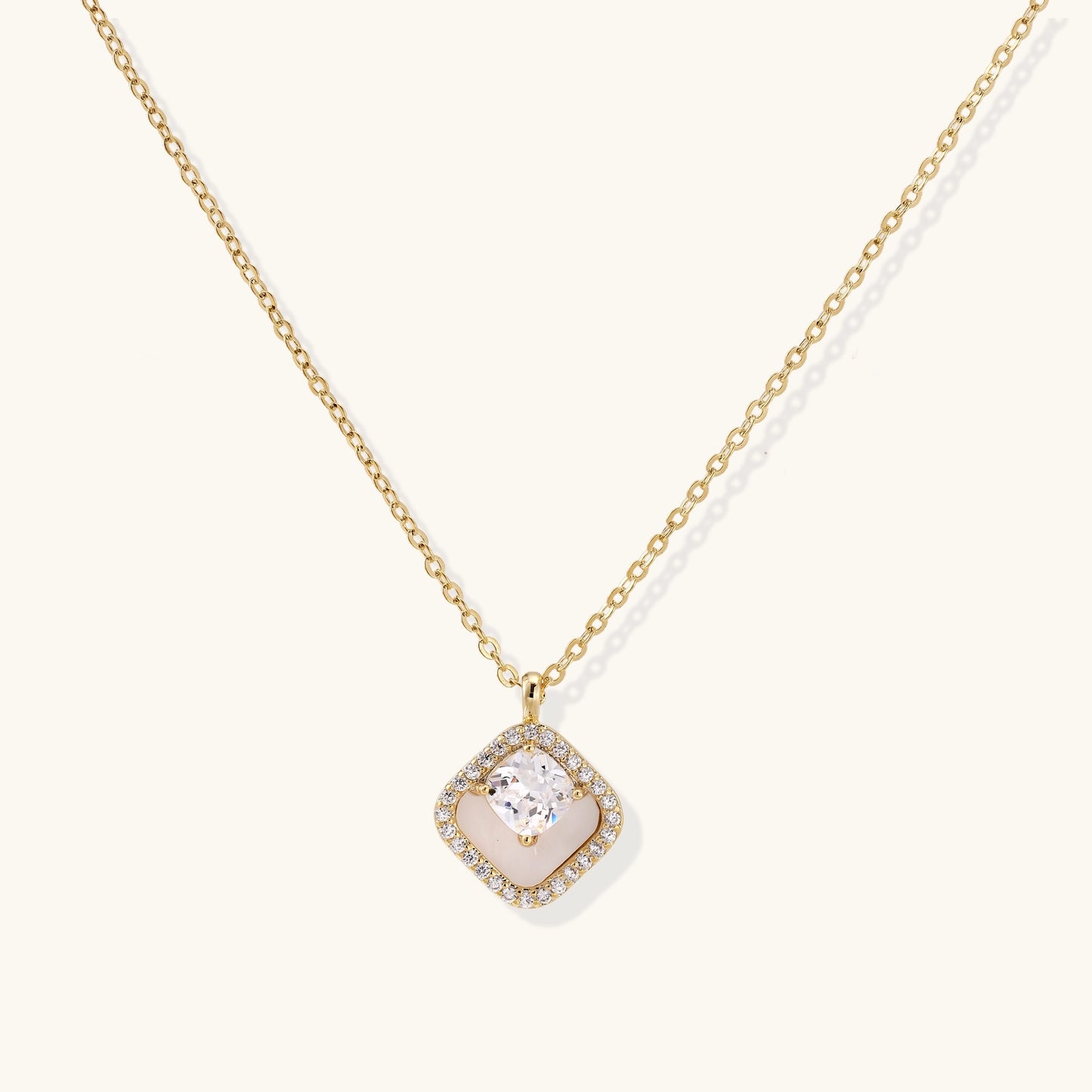 Gold-plated necklace with cushion-shaped pendant featuring a freshwater pearl surrounded by crystal halo on white background.