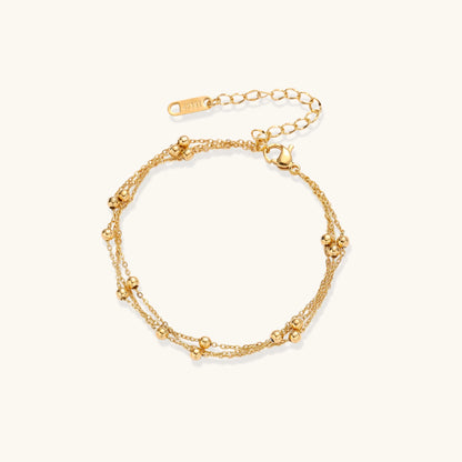 Delicate 18K gold plated bracelet with spherical beads on layered chains and adjustable extender on white background