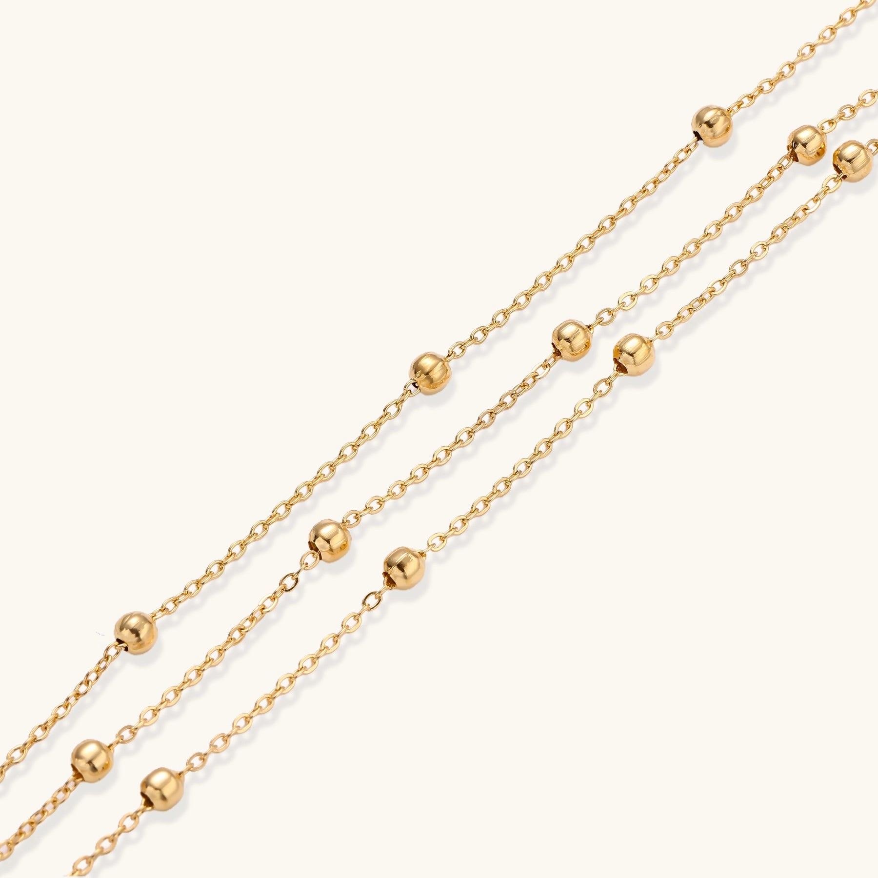 Delicate 18K gold plated bracelet with spherical beads on layered chains and adjustable extender on white background
