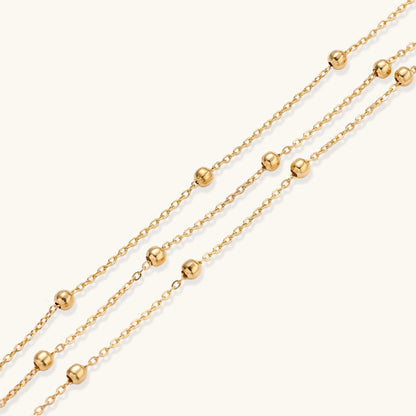 Delicate 18K gold plated bracelet with spherical beads on layered chains and adjustable extender on white background