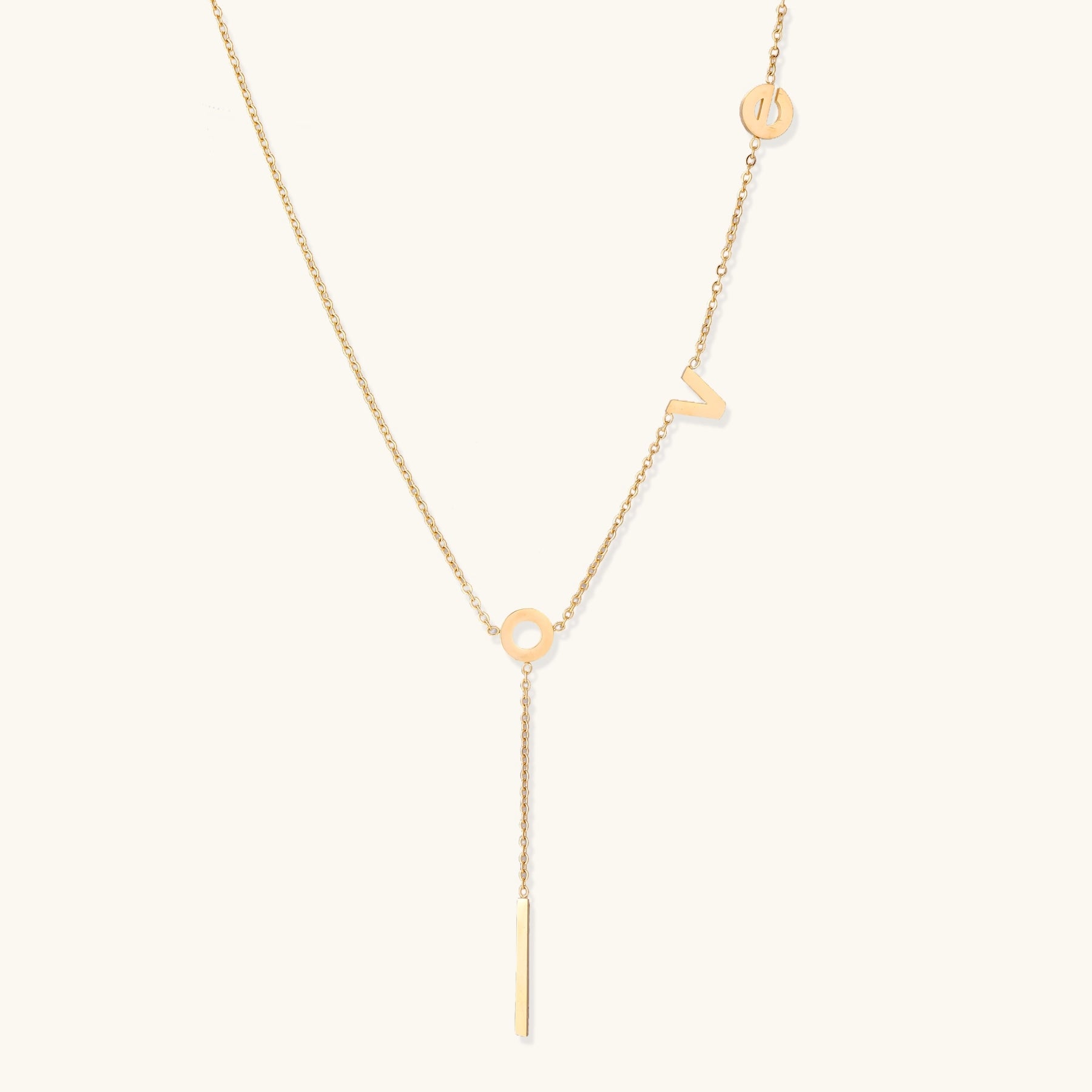 Gold-plated lariat necklace spelling LOVE with letter charms and vertical bar pendant on white background.
