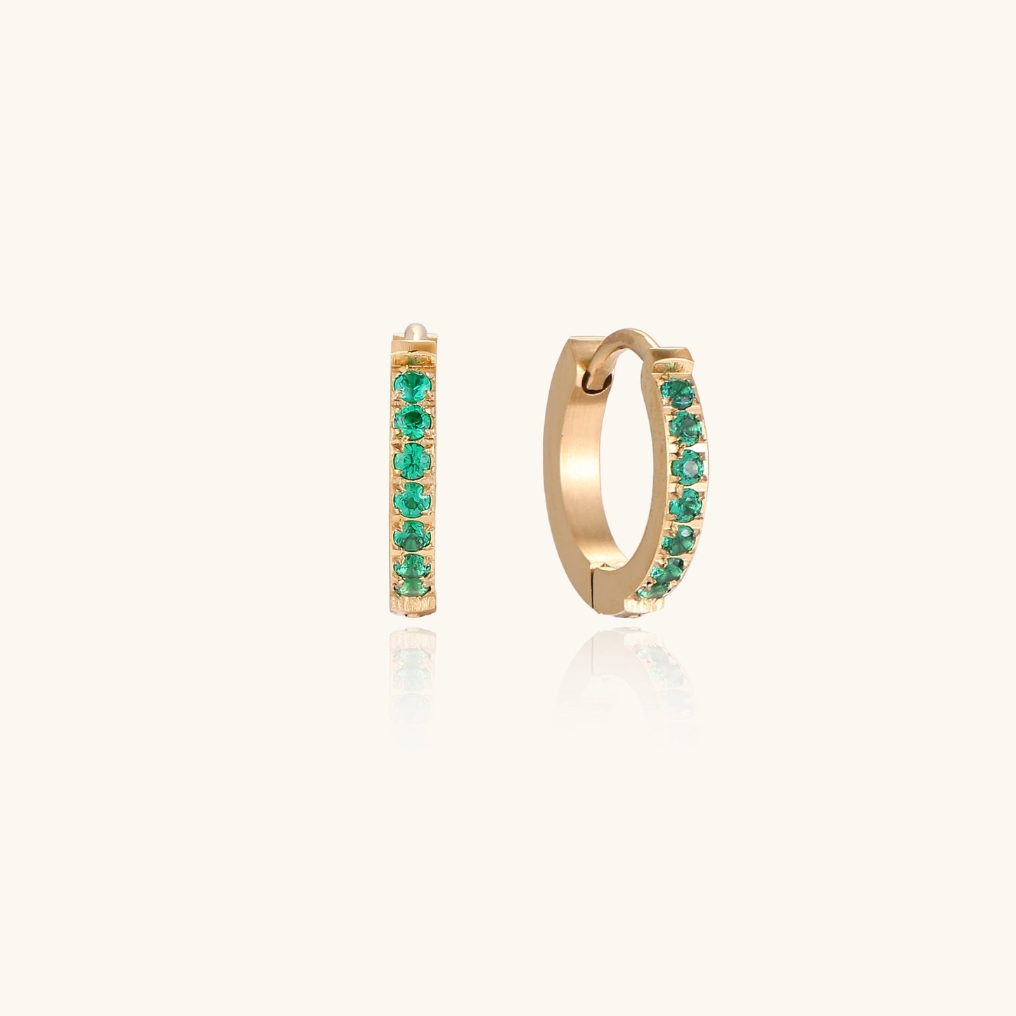 Small gold-plated huggie hoop earrings with emerald green cubic zirconia stones, one open showing hinge mechanism